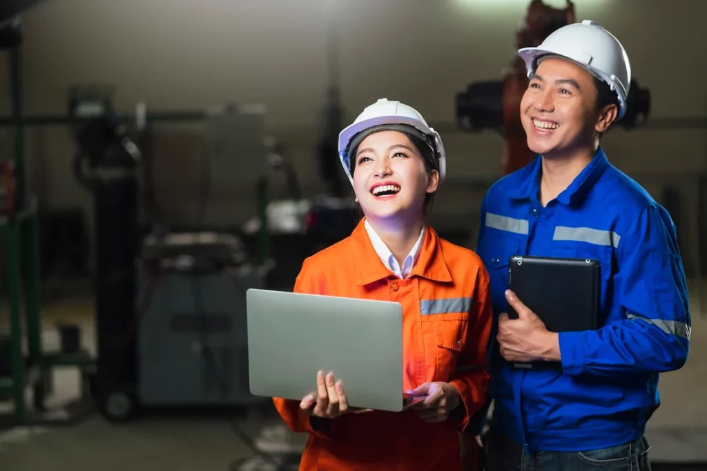 Hai kỹ sư sử dụng máy tính và máy tính bảng trong nhà máy