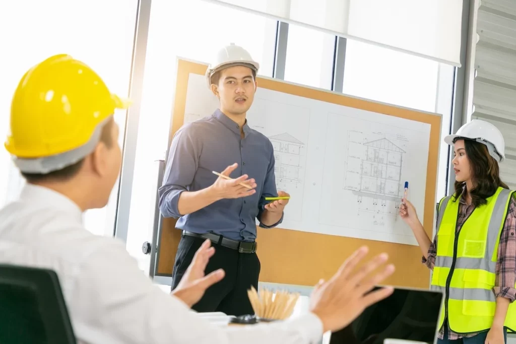 Kỹ sư châu Á trình bày bản vẽ kỹ thuật trước nhóm làm việc